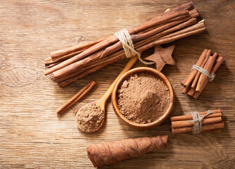 Cinnamon sticks and bowl of cinnamon powder on a wooden table