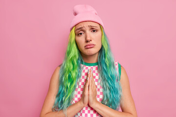 Beautiful upset teenage girl asks for favor keeps palms pressed together says please makes clingy...