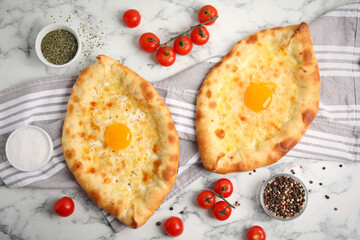 Fresh delicious Adjarian khachapuris served on white marble table, flat lay