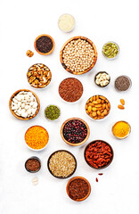 Set of superfoods, legumes, cereals, nuts, seeds in bowls on white table. Copy space, top view