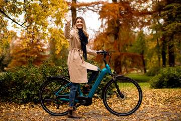 Young woman with electric bicycle in te autumn park