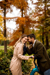 Young couple in the autumn park with electrical bicycle