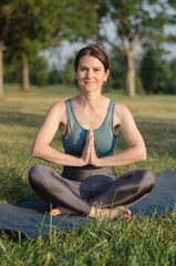 Fototapeta na wymiar Beautiful young woman meditates in the park at sunset. Healthy lifestyle