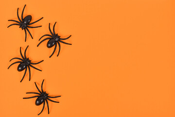 Plastic spiders on side of bright orange Halloween background with empty copy space - Powered by Adobe