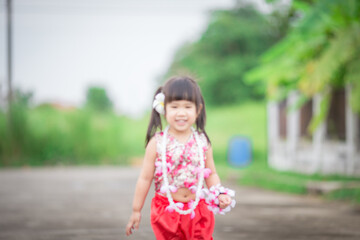Close-up background view of a blurred Asian girl running or teasing in the street in front of the...