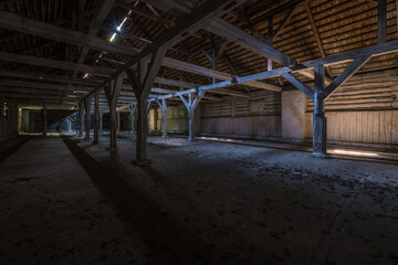 inside dark abandoned ruined wooden decaying hangar with rotting columns