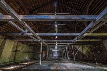 inside dark abandoned ruined wooden decaying hangar with rotting columns