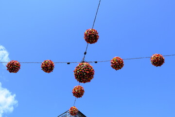 Nice flower monuments hanging at thin lines in the blue sky. One sunny summer day outside. Artful round flowerballs. Outside fresh construction. Karlstad, Värmland, Sweden, Europe. - Powered by Adobe