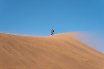 Fototapeta na wymiar Positive attitude towards life. People walking on the sand dunes. Namibia, Africa.