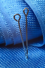 two sewing pins on a background of blue fabric. close-up.