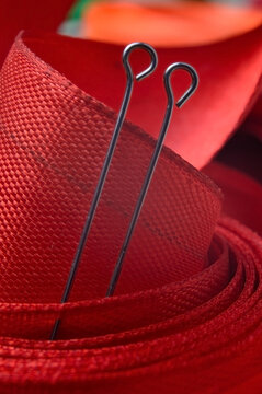 two sewing pins on the background of a red cloth tape. close-up.
