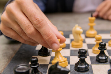 A man makes a move of a chess piece of a white queen on a board