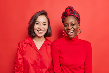 Horizontal shot of happy mixed race women friends smile positively enjoys nice day spend free time...