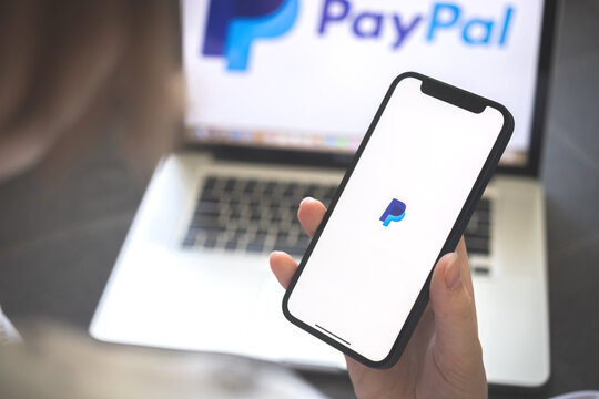 Kharkov, Ukraine - August 12, 2021: Paypal app. Woman using smartphone with paypal application. Brand logo photo