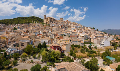 Fototapeta na wymiar An aerial view with the drone of the mountain village of Moratalla in Spain. You can see the roofs and the church well. It's summer and there are beautiful clouds in the sky.