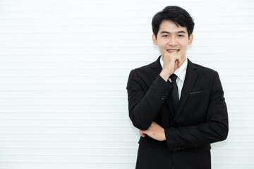 Portrait attractive young business executive with formal black suit standing and thinking in his office, looking at camera isolated over white background.