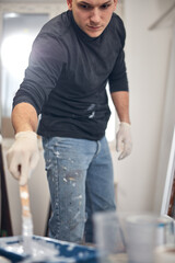 Young adult man painting on a DIY budget renovation of his new home apartment.