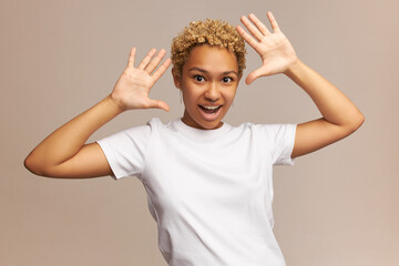 Portrait of happily surprised ethnic woman with blonde wavy hairstyle, with palms up, shouting and...