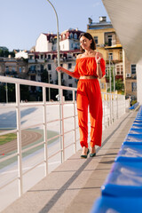 Stylish woman in orange clothes  at sunset at cycle track stadium posing