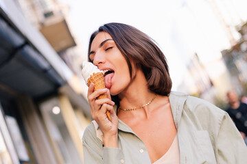 Woman outdoor  at summer sunset time having ice cream cone positive happy playful at city street