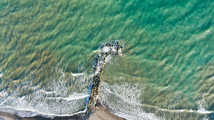 Shooting of the sea azure pier from a drone. Top view of the sea with stones