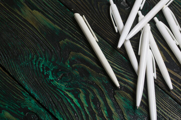 A set of white fountain pens for school. They lie on pine boards.