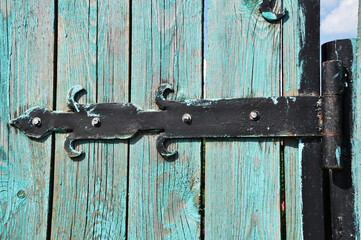 Forged metal hinges of an old wooden door. Background, texture, design.