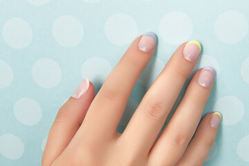 Beautiful womans hand with spring summer nail design on blue background