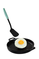 Levitation food with a fried egg and a silicone spatula falling on a black ceramic pan.