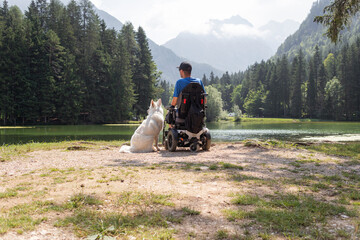 Disabled man on wheelchair with his dog on a trip in nature.