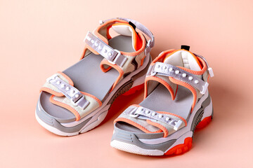 Women's, fashionable, sports sandals with orange accents on a pink background. New youth shoes for...