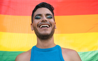 Happy homosexual man celebrating gay pride holding rainbow flag symbol of LGBTQ community