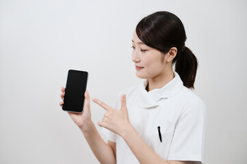 スマートフォンを操作する白衣の女性 