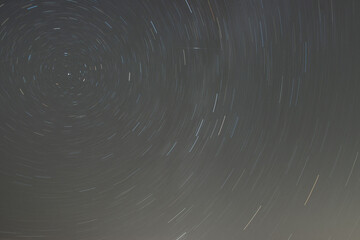 Stars rotate around the polar star in the night sky forming star trails