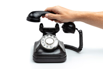 MALE HAND LIFTING OLD ROTARY DIAL BLACK PHONE ISOLATED ON WHITE BACKGROUND.