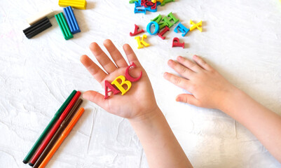 child holding ABC letters in hands over desk table background Education and development concept.