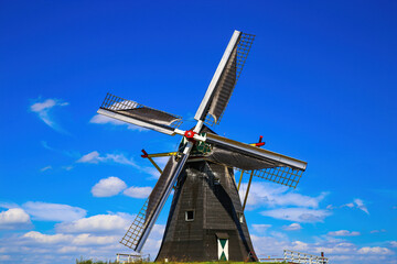 Beesel, Netherlands - July 9. 2021: View on isolated typical dutch windmill (Molen de grauwe beer) in rural landscape against deep blue summer sky with cumulus clouds