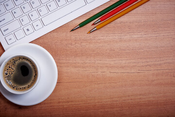 Wooden desk office with pc cayboard, and other work supplies with cup of coffee. Top view with copy space for input the text. Designer workspace on desk table essential elements on flat lay