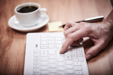 Woman works in the office on a wooden table. Woman's hand on keyboard. Concept workspace, working at a computer, freelance, design. Cayboard and cup of coffee. Flat lay, top view.