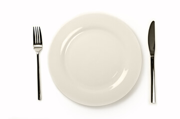 Empty white plate with fork and knife on table. Top view.