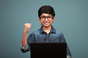 Smiling boy shows cheering gesture while learning through laptop