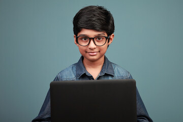 Smiling boy looks while learning through his laptop