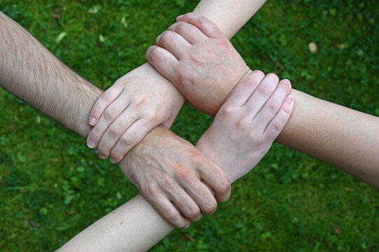 Raute aus vier einander am Handgelenk fassenden Händen