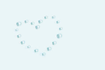 Heart shaped transparent water drops. Light delicate blue tone background.