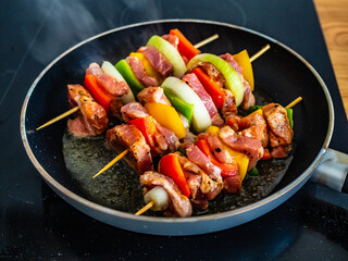 Uncooked skewers in frying pan
