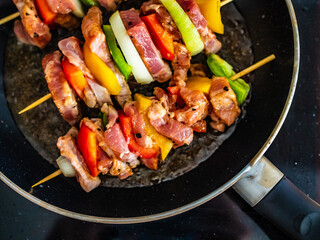 Uncooked skewers in frying pan
