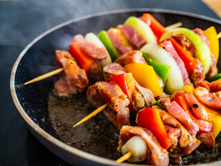 Uncooked skewers in frying pan
