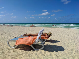 Cayo Coco, Cuba, 16 may 2021: People relax, sunbathe and swim at cuban beach. Woman in a hat lies...