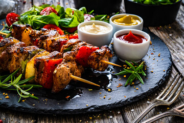 Skewers - grilled meat with fresh vegetables on wooden background
