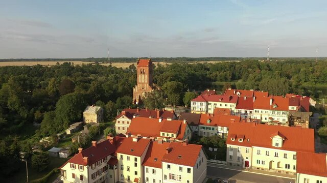 Aerial: The restored facades of the Zheleznodorozhny town on the background of an abandoned old Prussian church, Russia